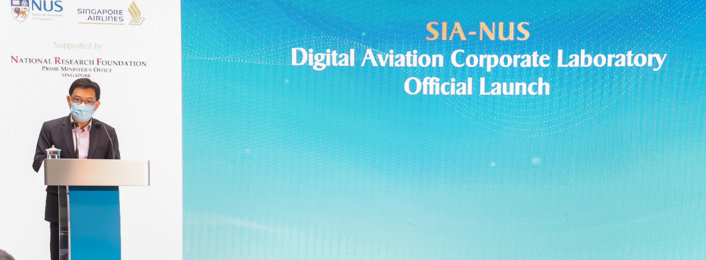 Masked person at podium; NUS & Singapore Airlines logos above "SIA-NUS Digital Aviation Corporate Laboratory Official Launch".